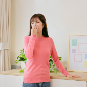 Lady holding her nose wondering what the smell is in her house